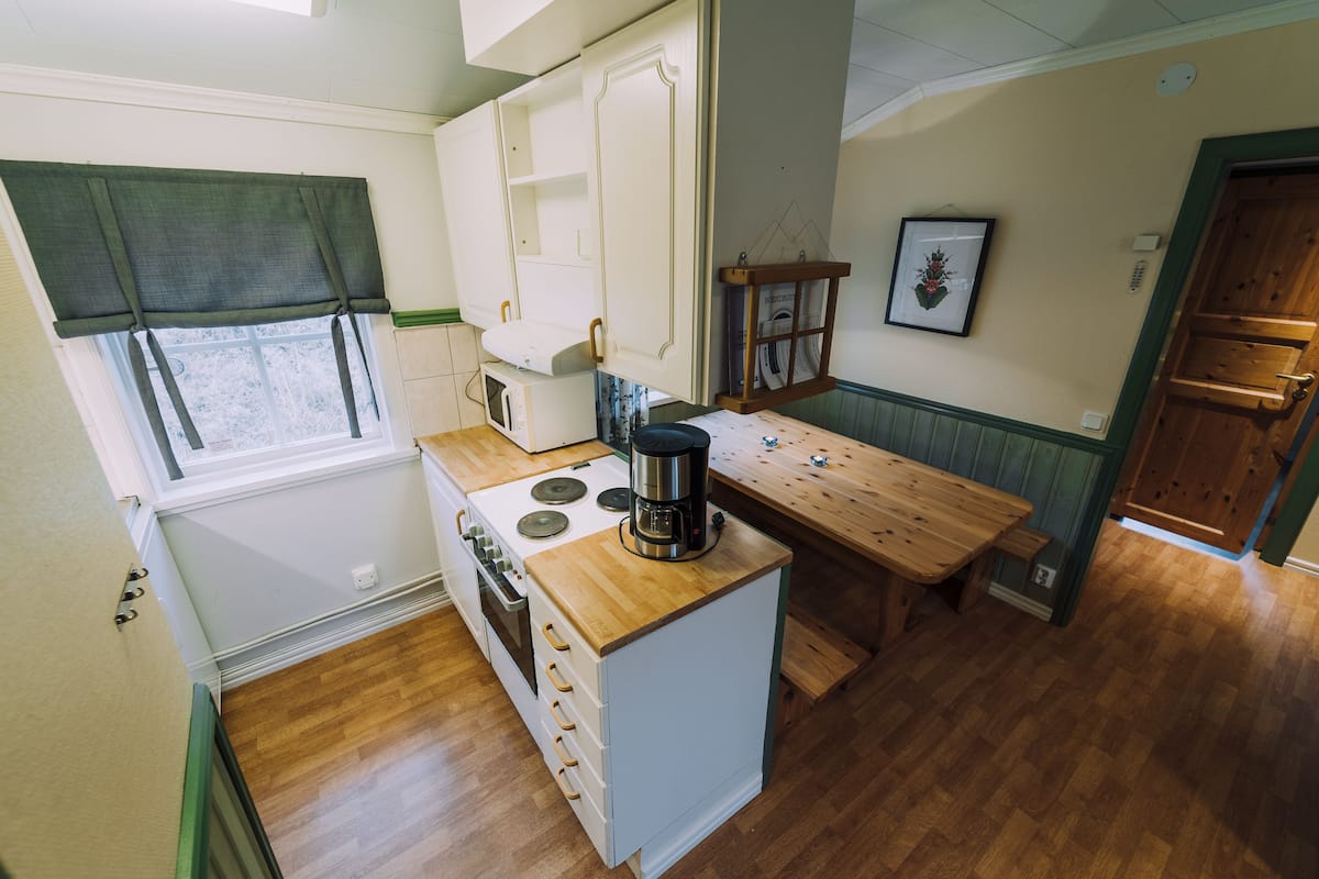 A compact kitchen with a wooden countertop, a stove, and a coffee maker.