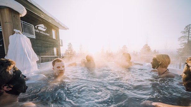 A group of people in a hot tub outside a wooden building with a sign that reads "Fernilla Wiberg Hotel". - Idre Fjäll Stugor och Lägenheter (Idre)