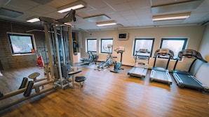 A gym with various exercise equipment, large windows, and a wooden floor. - Idre Fjäll Stugor och Lägenheter (Idre)
