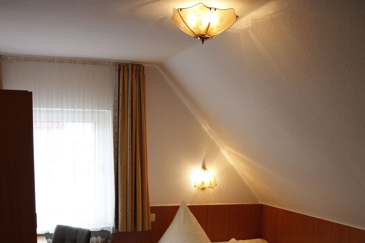 A small, cozy room with a bed, a desk, and a chair.