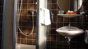 A bathroom with a glass-enclosed shower, a sink, and a mirror. - Hotel Pellmühle (Jever)