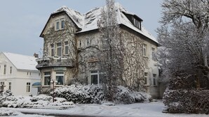 A historic building with a stone facade, a balcony, and a sign indicating it is a hotel. - Hotel Pellmühle (Jever)