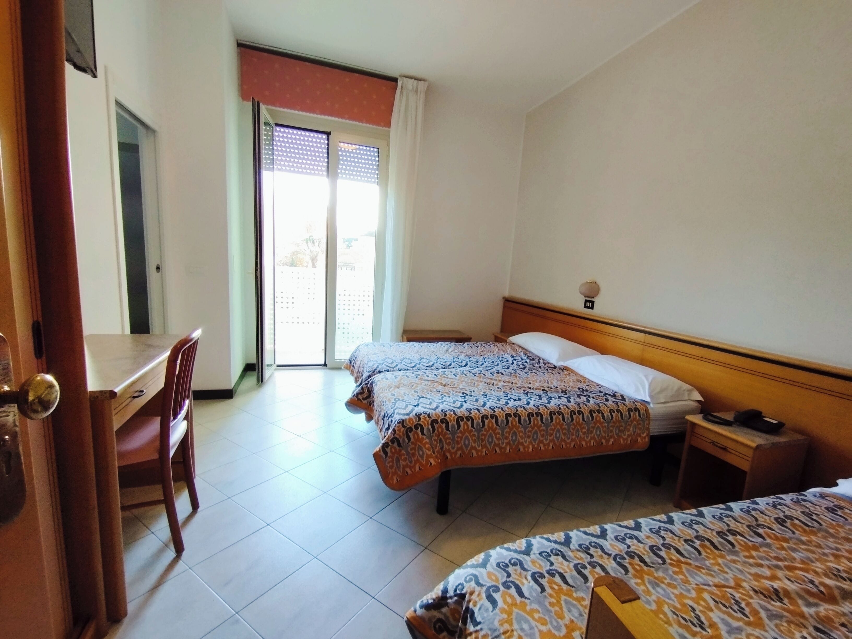 A hotel room with two beds, a desk, and a chair.
