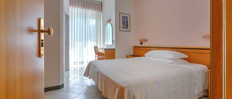 Quarto de hotel com uma cama, uma escrivaninha e uma cadeira.