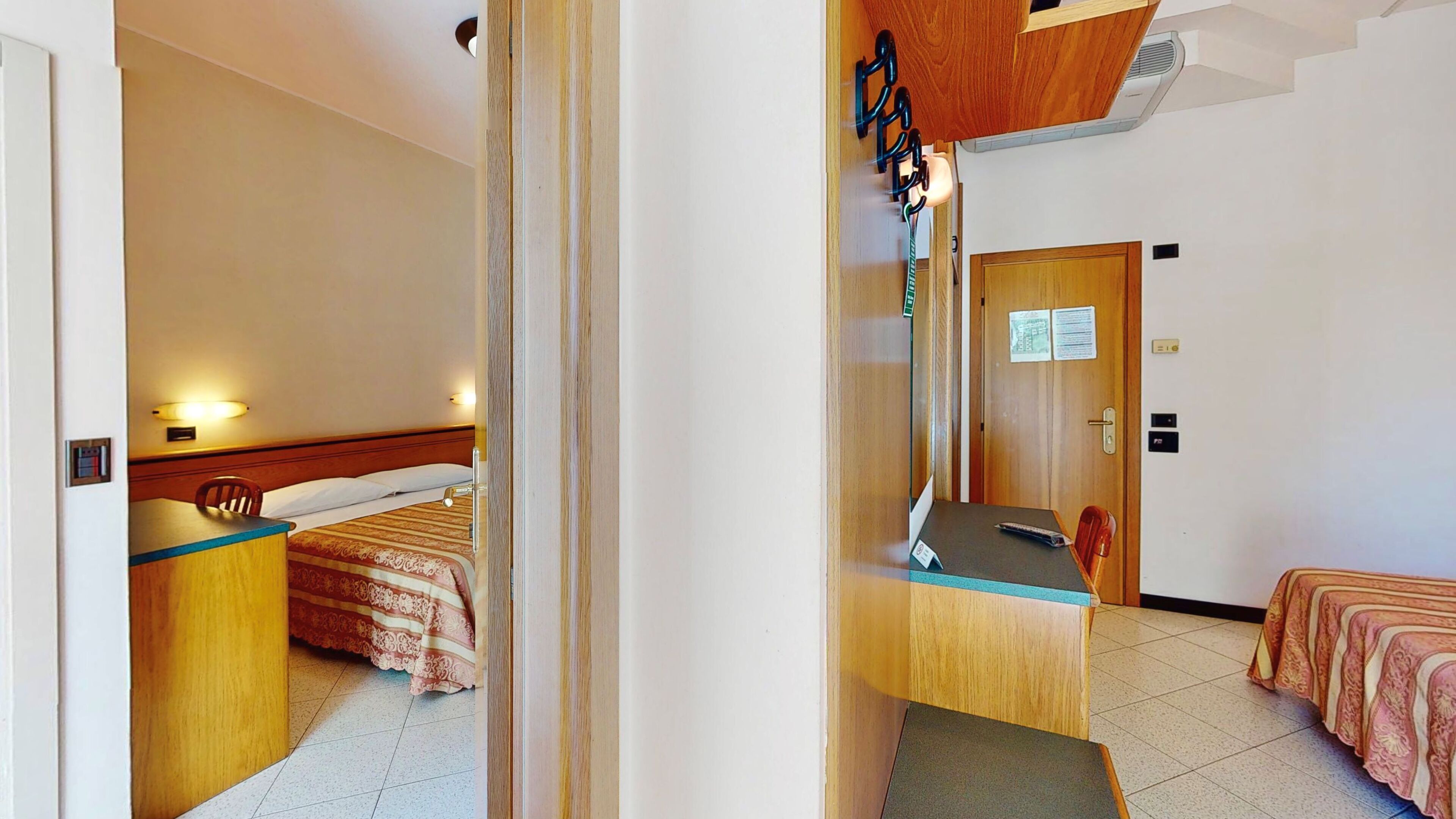 A hotel room with a bed, a desk, a chair, a small table, and a wooden cabinet.