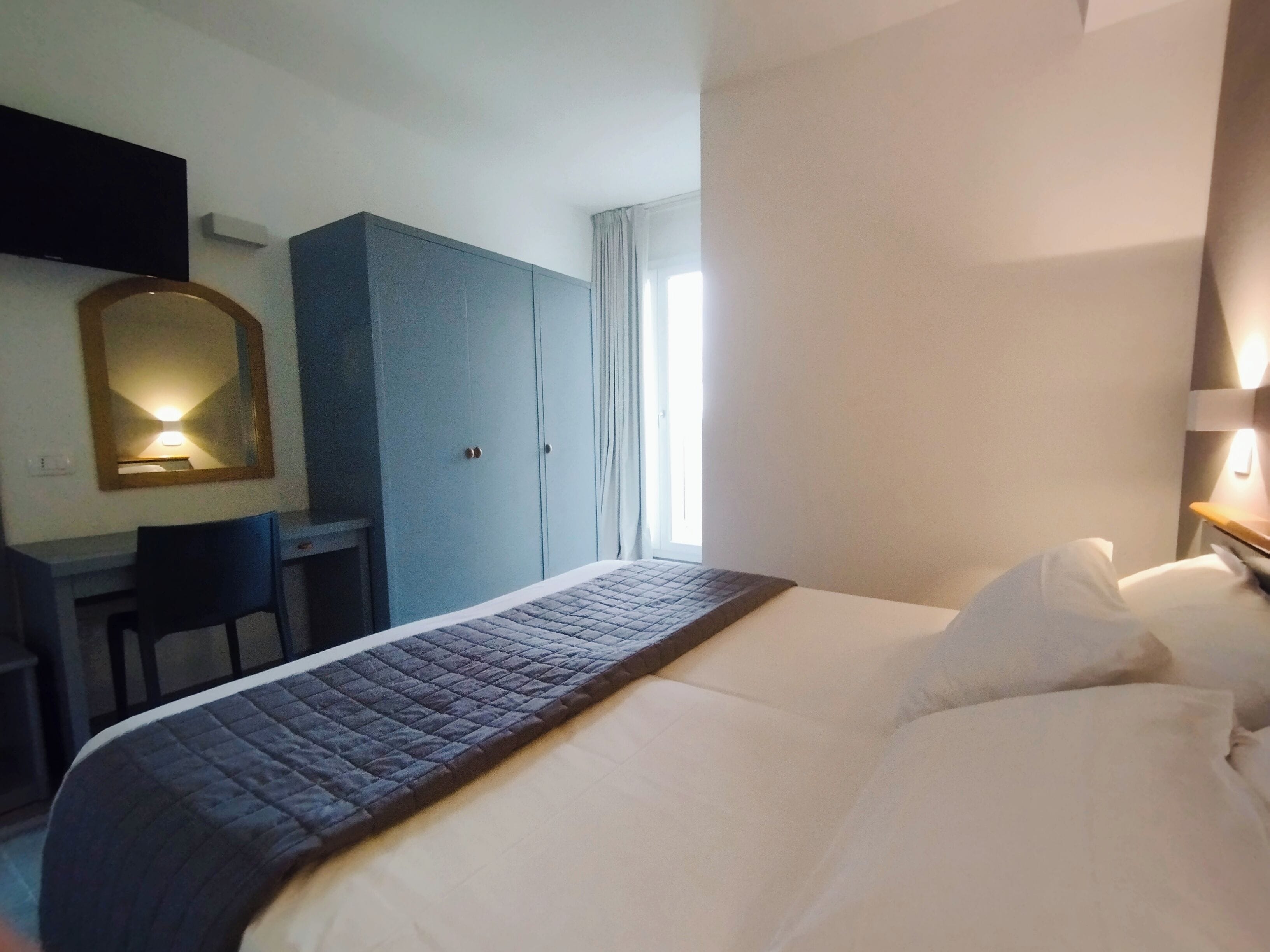 A hotel room with a bed, a desk, and a wardrobe.