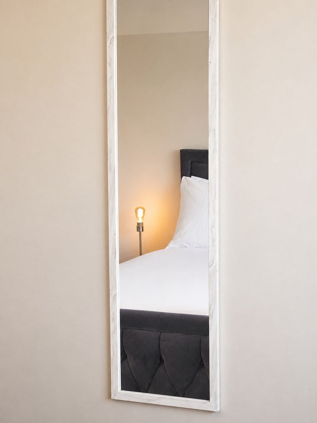 Ein Bett mit Kopfteil, einer Nachttischlampe und einem Spiegel.