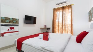 A hotel room with a bed, a TV, a desk, and a window with curtains. - RedDoorz Plus @ Boulevard Residence BSD (South Tangerang)