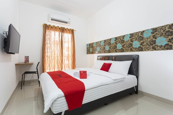 A hotel room with a bed, a chair, a TV, and a wall-mounted air conditioner. - RedDoorz Plus @ Boulevard Residence BSD (South Tangerang)