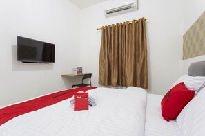 Una habitación de hotel con cama, televisión, escritorio y silla.