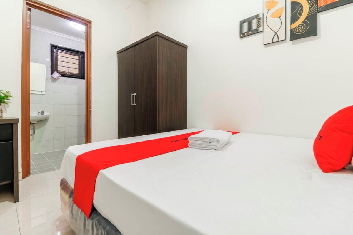 A hotel room with a bed, a wardrobe, a sink, and a mirror.