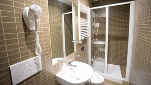 A bathroom with a hairdryer mounted on the wall, a sink, a mirror, and a shower enclosure. - Funny Palace Hostel (Rome)