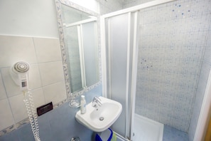 Casa de banho com lavatório branco, espelho e cabine de duche.