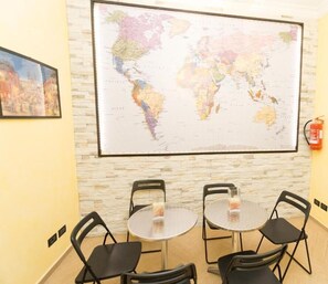 A conference room with a large world map on the wall, two round tables, and four black chairs. - Funny Palace Hostel (Rome)