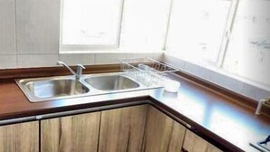A kitchen with a double sink, wooden cabinets, and a window providing natural light. - Laguna del Mar (La Serena)