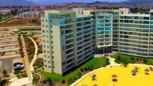 A modern multi-story hotel with a central courtyard and a pool area. - Laguna del Mar (La Serena)