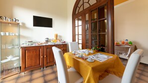 A dining area with a table set for four, a kitchen area with cabinets and a countertop, and a large window with a view.