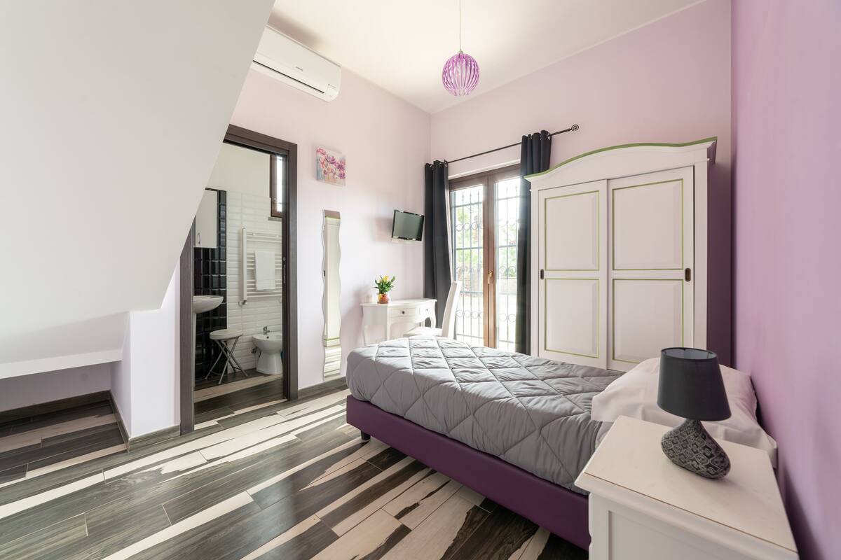 A bedroom with a bed, bedside table, and a TV.