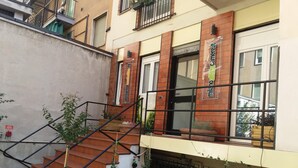 A building with a staircase leading to a landing with potted plants. - Milano Affittacamere (Milan)