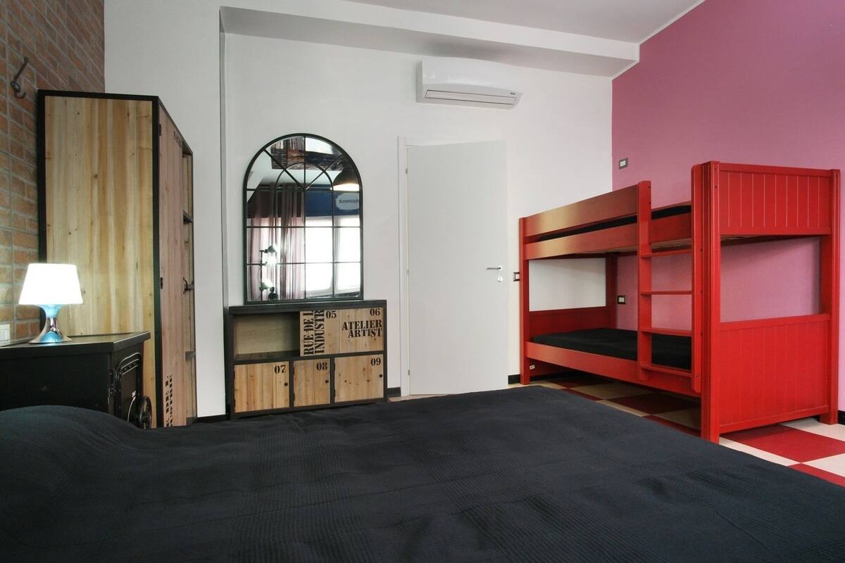 A bedroom with a bunk bed, a wooden dresser, a mirror, and a lamp.