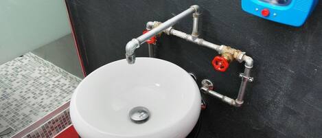 Et badeværelse med en hvid vask, sorte vægge og en blå sæbedispenser.