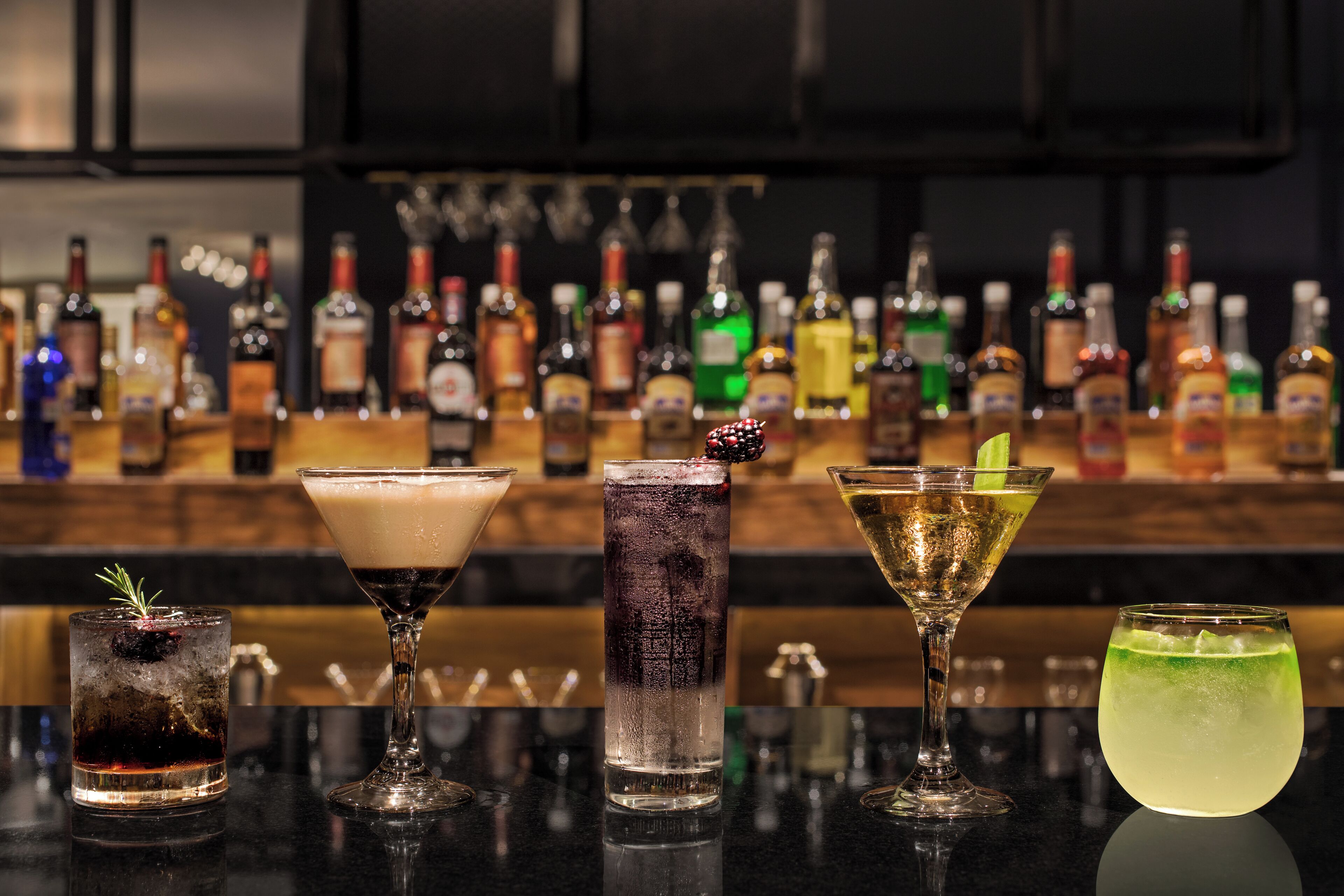 Eine Bar mit verschiedenen Cocktails und Flaschen im Hintergrund.