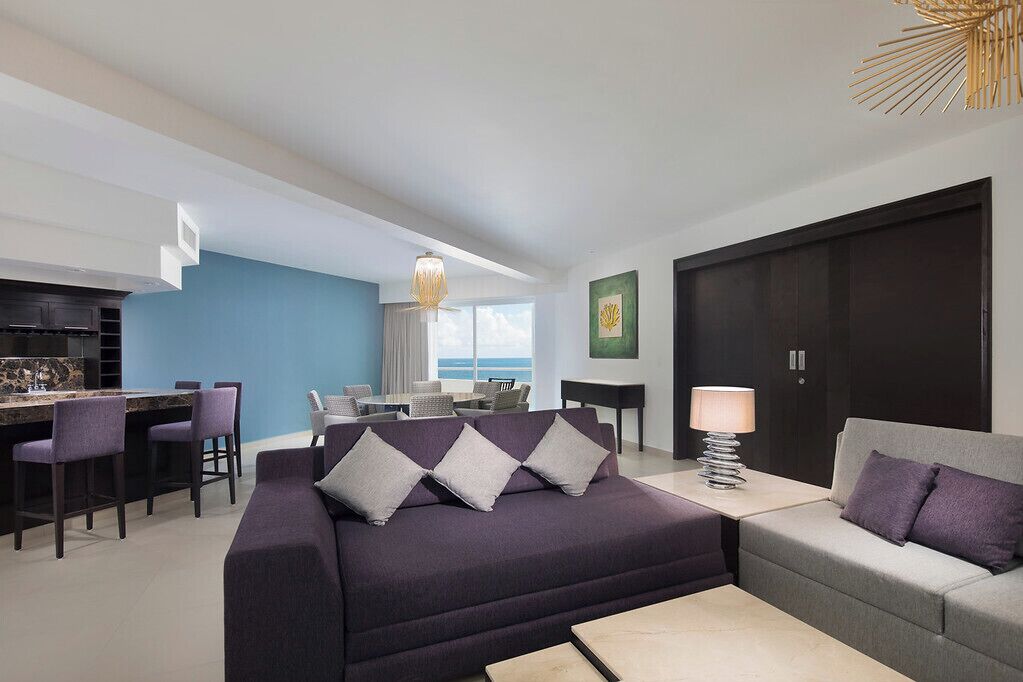 Un salon moderne comprenant un canapé, une table basse et un coin repas avec des chaises et une table.