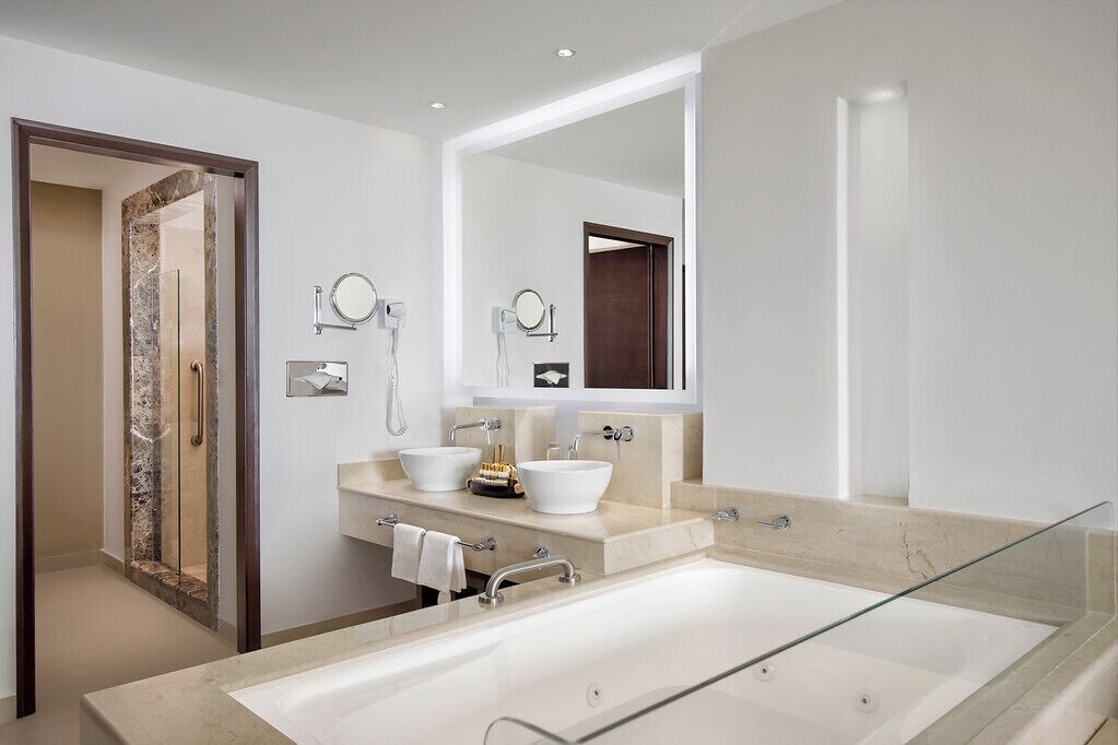 Une salle de bain moderne avec une grande baignoire, deux lavabos et un miroir.