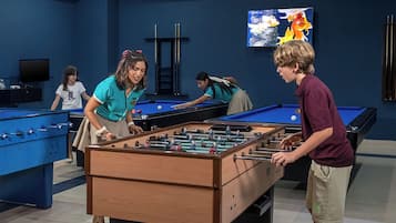Um bar com várias mesas de futebol de mesa e uma mesa de bilhar.