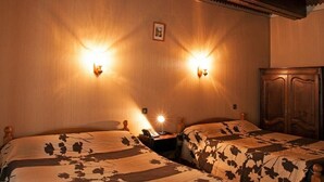 Een kamer met twee bedden, houten hoofdborden en wandlampen.