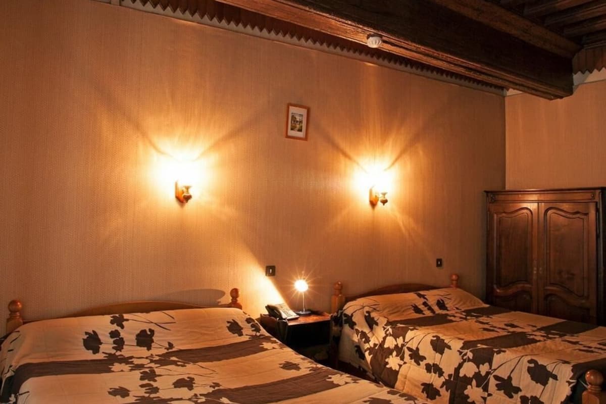 Een kamer met twee bedden, houten hoofdborden en wandlampen.