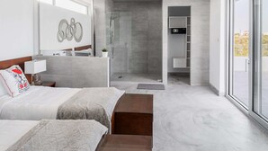 A modern hotel room with a large bed, a bathroom with a shower, and a view through a glass door. - White Villas (Providenciales)