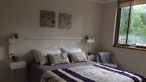 Quarto com cama, mesas de cabeceira, janela e obras de arte na parede.
