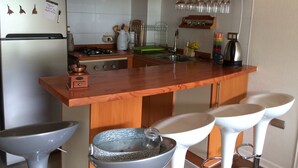 Uma cozinha com armários de madeira, uma ilha central com bancos, uma pia e um fogão.
