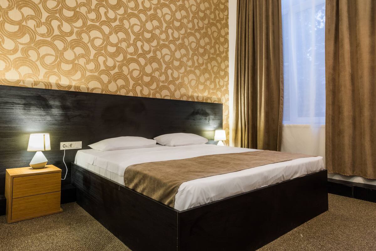 Une chambre d’hôtel avec un grand lit, des lampes de chevet, une table de chevet et un papier peint à motifs.
