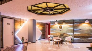 Ein modernes Interieur mit einem geometrischen Deckendesign, einem runden Tisch in der Mitte und einer Wand mit Holzapplikationen.