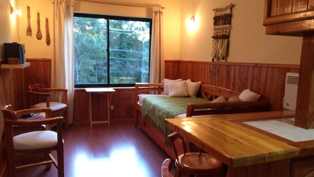Una habitación acogedora estilo cabaña con una cama de madera, un escritorio y dos sillas.