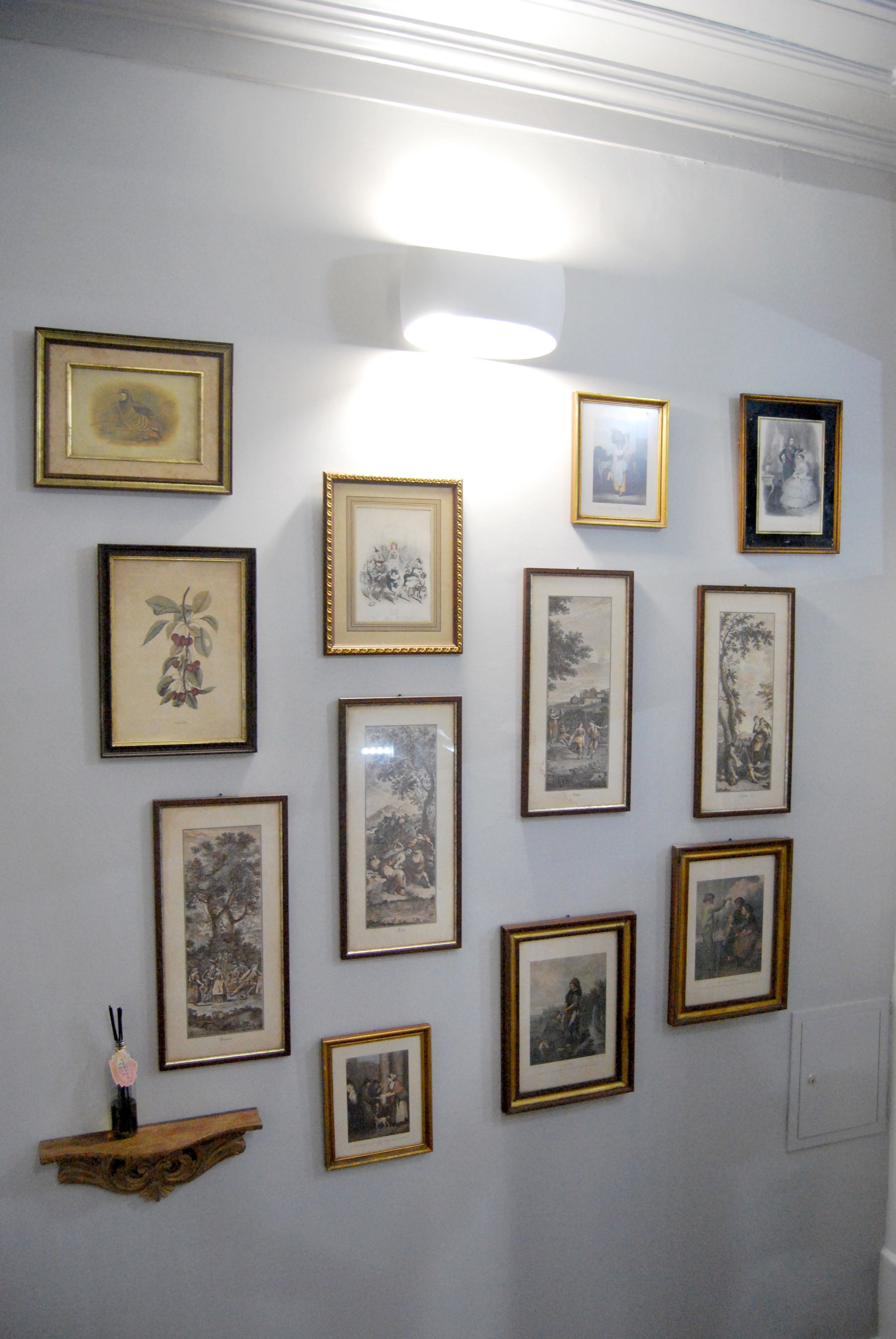 A wall with multiple framed artworks of various sizes and styles.