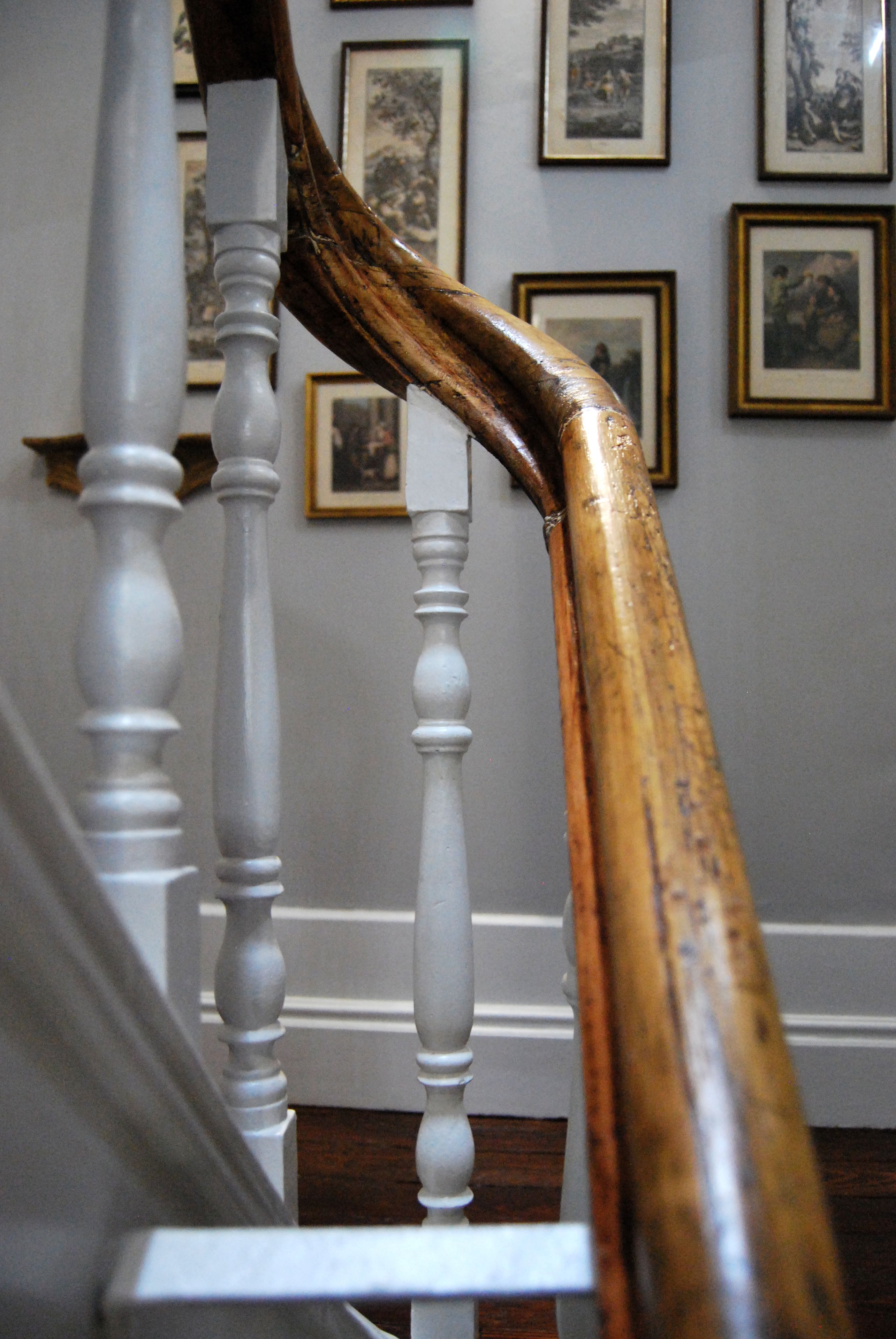 Una escalera con balaustres blancos y barandilla de madera.