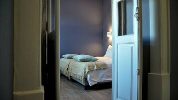 A bedroom with a bed, pillows, and a bedside table.