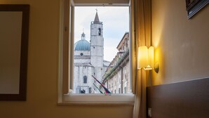 Une chambre d’hôtel avec vue sur un bâtiment historique, visible par la fenêtre.