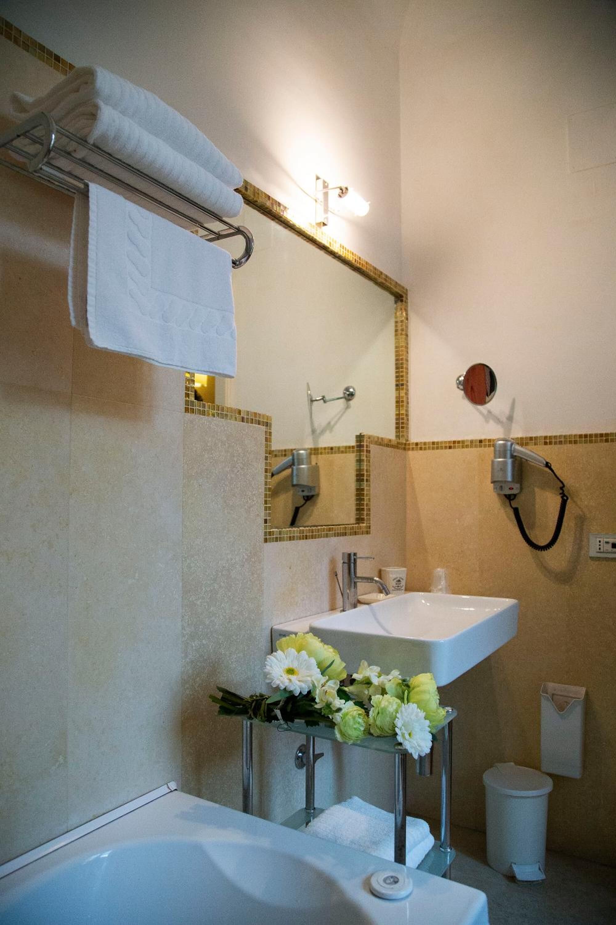 Un baño con bañera, dos lavamanos, un espejo y un perchero para toallas.