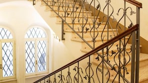 Un escalier orné de rampes en métal décoratif et recouvert d’un tapis à motifs.