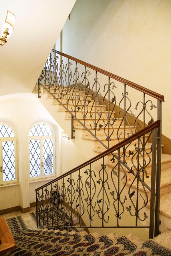 Una escalera con barandillas de metal decoradas y un suelo con diseño.