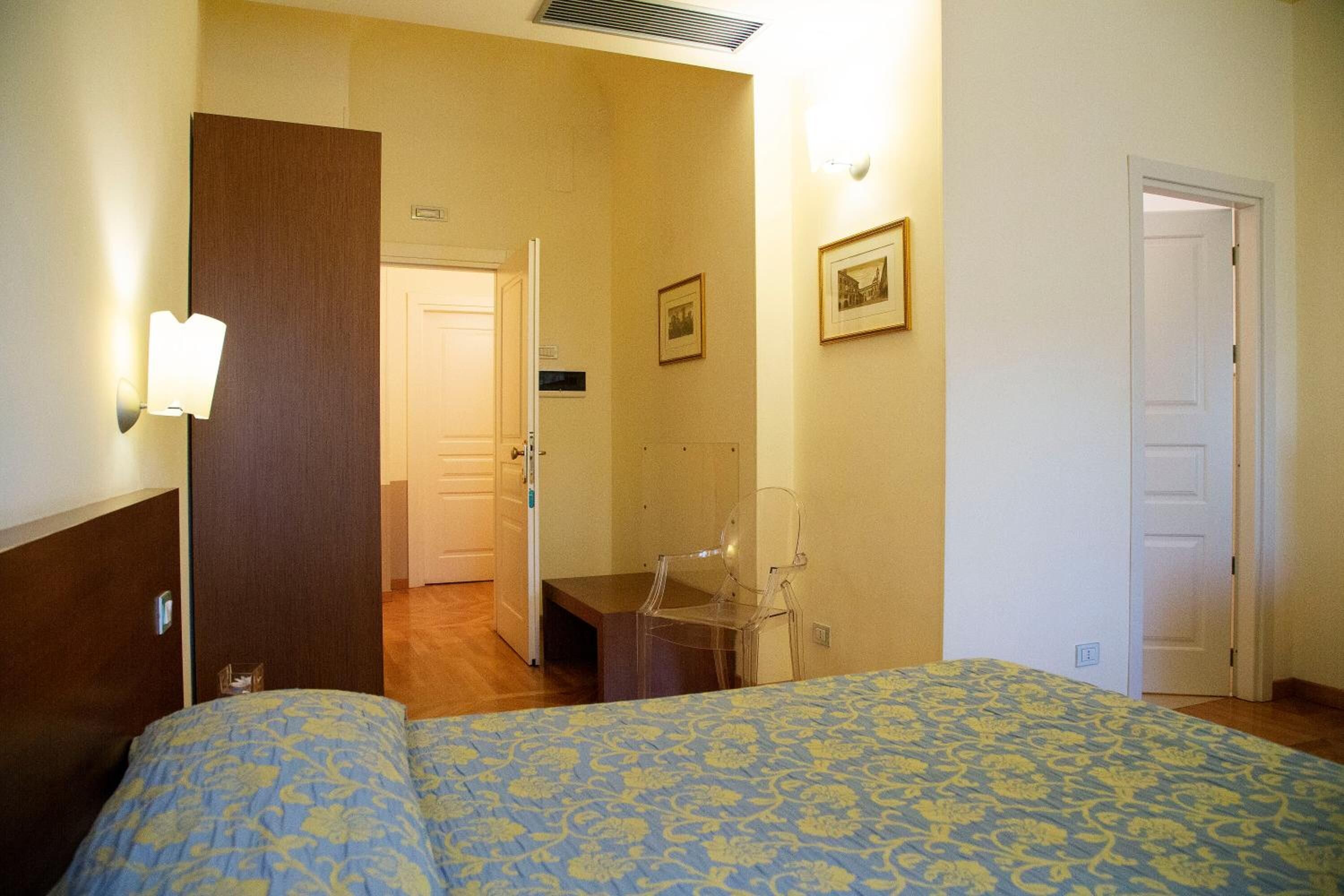 Una habitación de hotel con cama, una silla, un escritorio y una puerta.