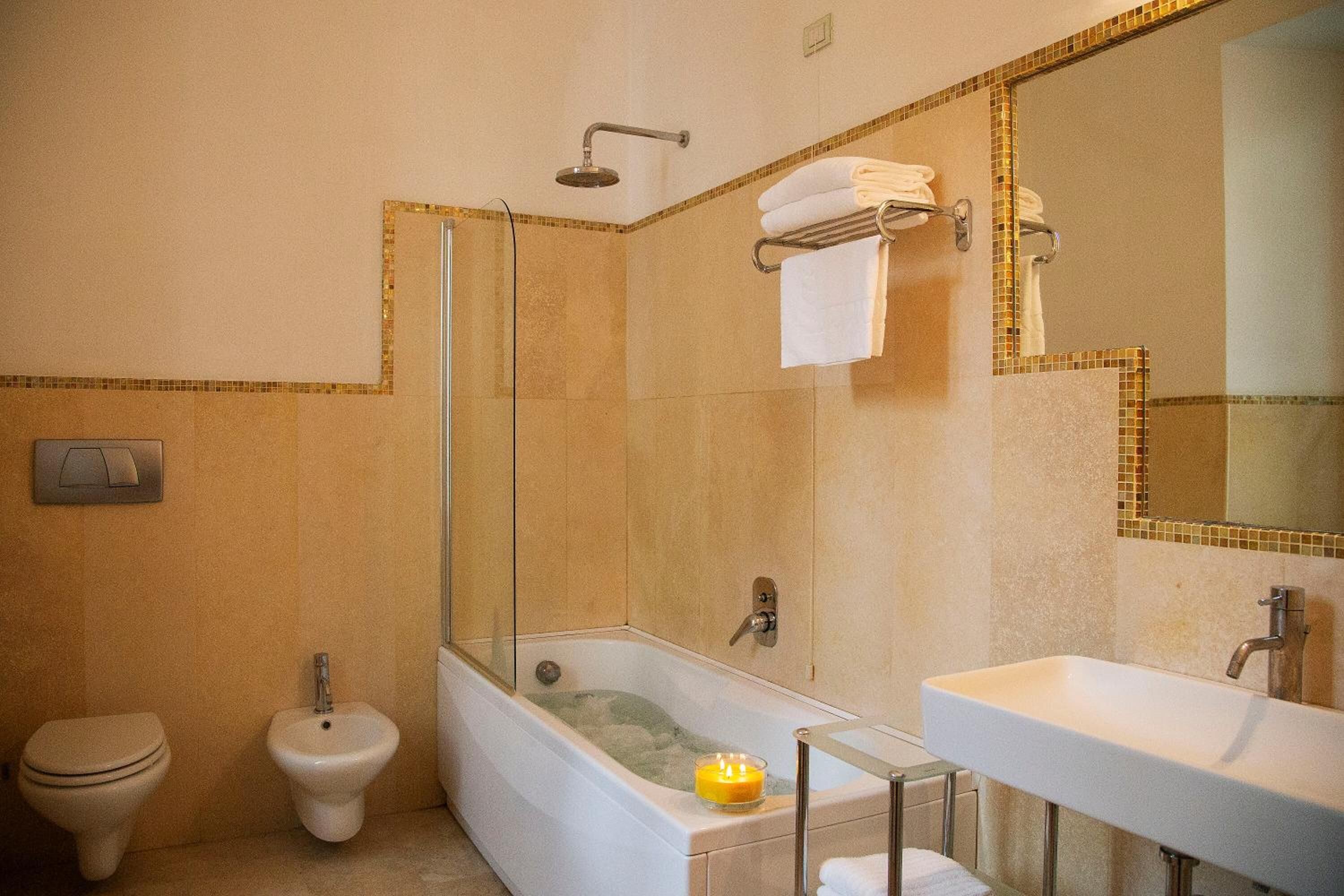 A bathroom with a bathtub, toilet, bidet, and a large mirror.