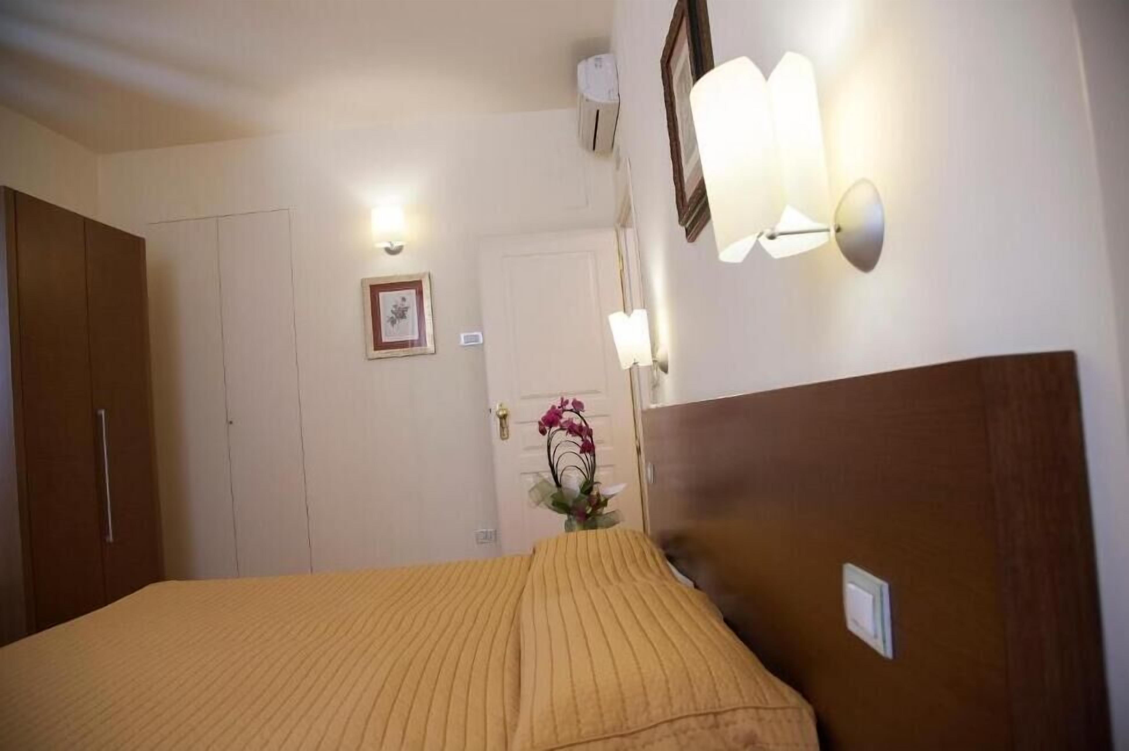 Ein Hotelzimmer mit Bett, Schrank, einer Tür und einer Wandleuchte.