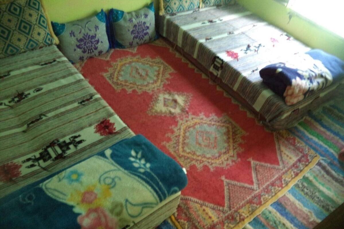 A room with a patterned sofa, a red rug, and a window with a view.