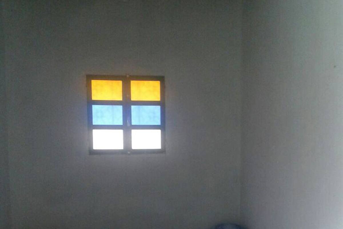 Una habitación con una cama, una ventana de cuatro cristales y techo de madera.