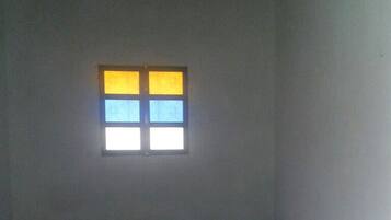 Una habitación con una cama, una ventana de cuatro cristales y techo de madera.